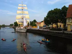 Dreimastiges Segelschiff an einer baumbestandenen Uferpromenade in Klaipėda